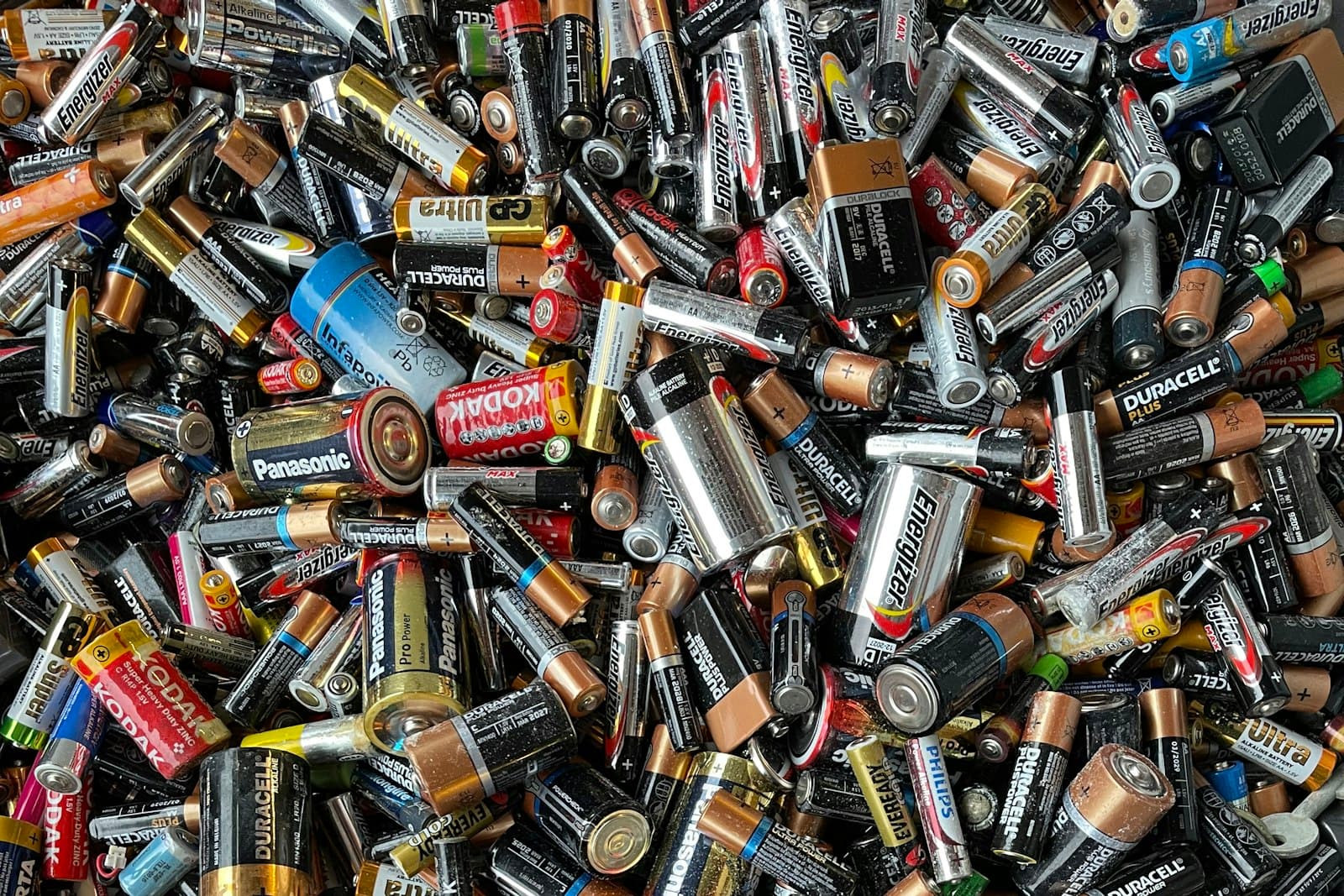A large pile of used household batteries collected together for recycling at a waste facility